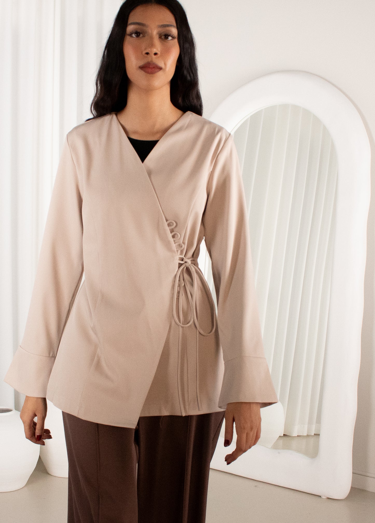 Woman wearing a beige wrap-style top with a white background