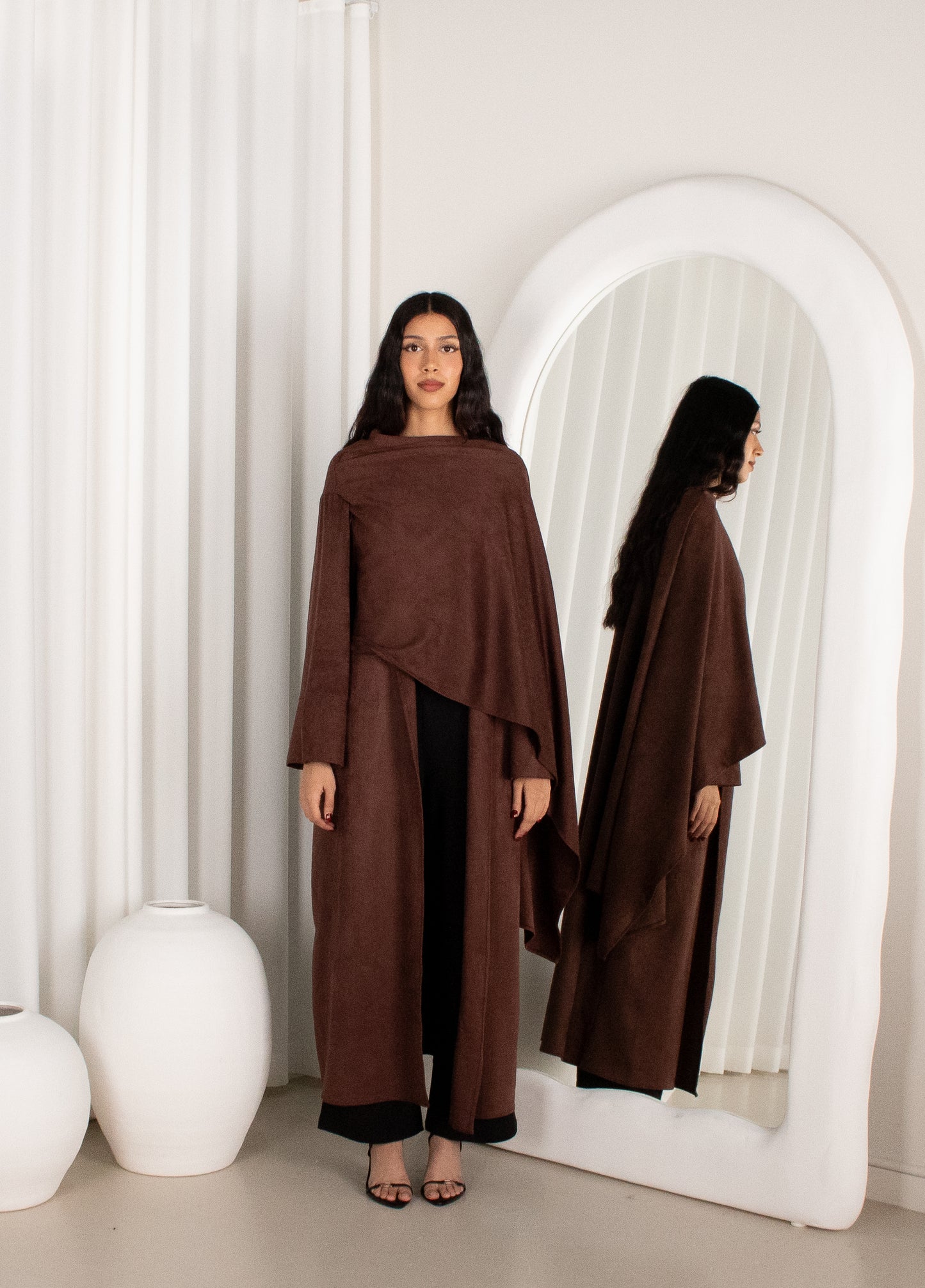 Woman wearing a brown outfit standing in front of a white mirror.