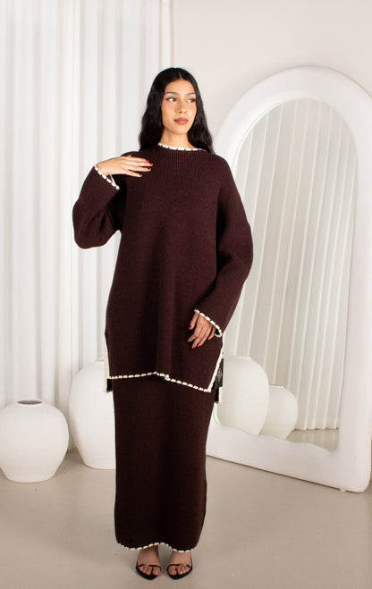 Woman wearing a brown dress with white trim in a minimalistic setting