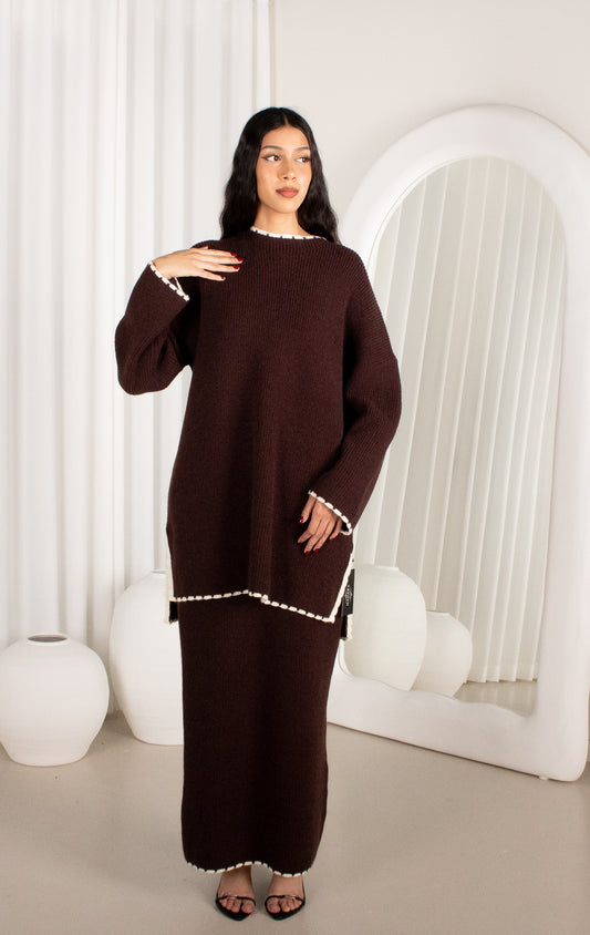Woman wearing a brown dress with white trim in a minimalistic setting