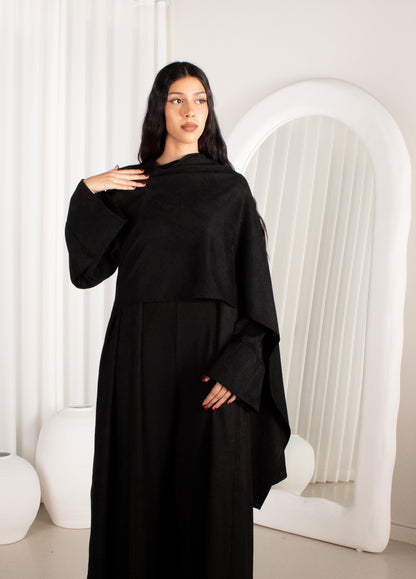 Woman wearing a black abaya in a minimalistic white room