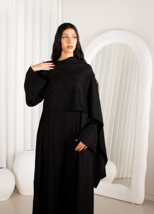 Woman wearing a black abaya in a minimalistic white room