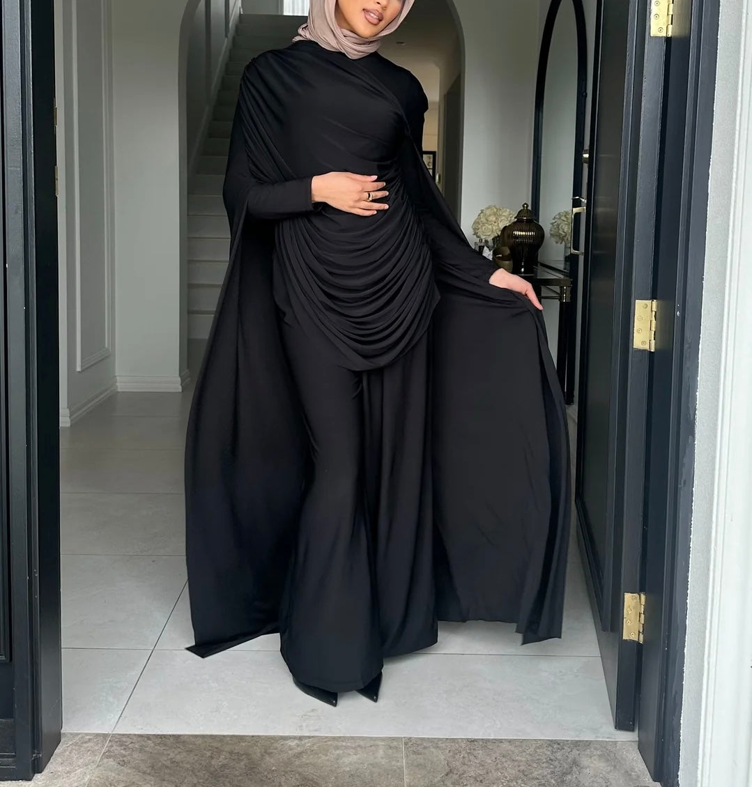 Person wearing a black abaya standing in a doorway.