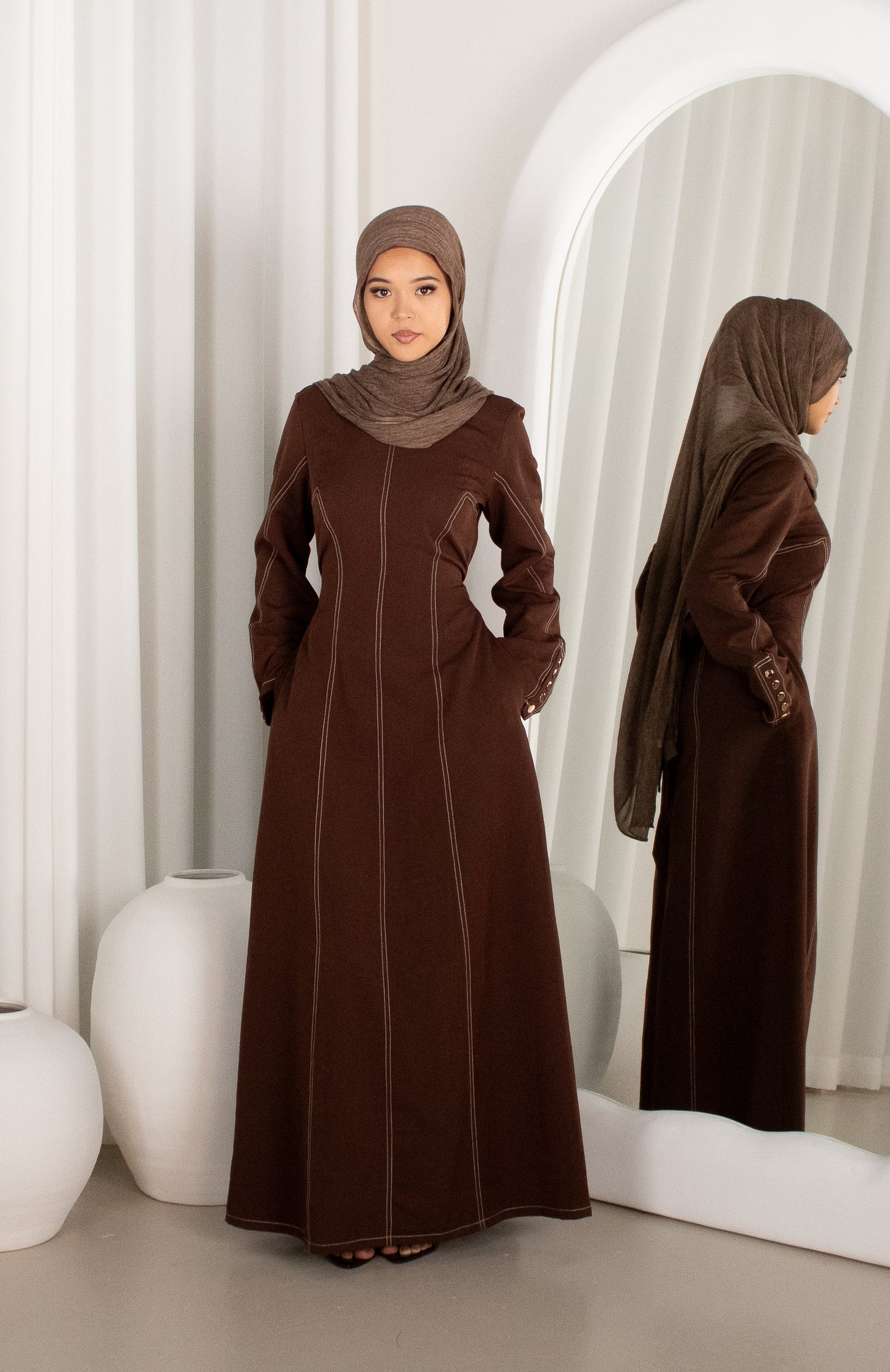 Woman wearing a brown abaya in a modern interior setting