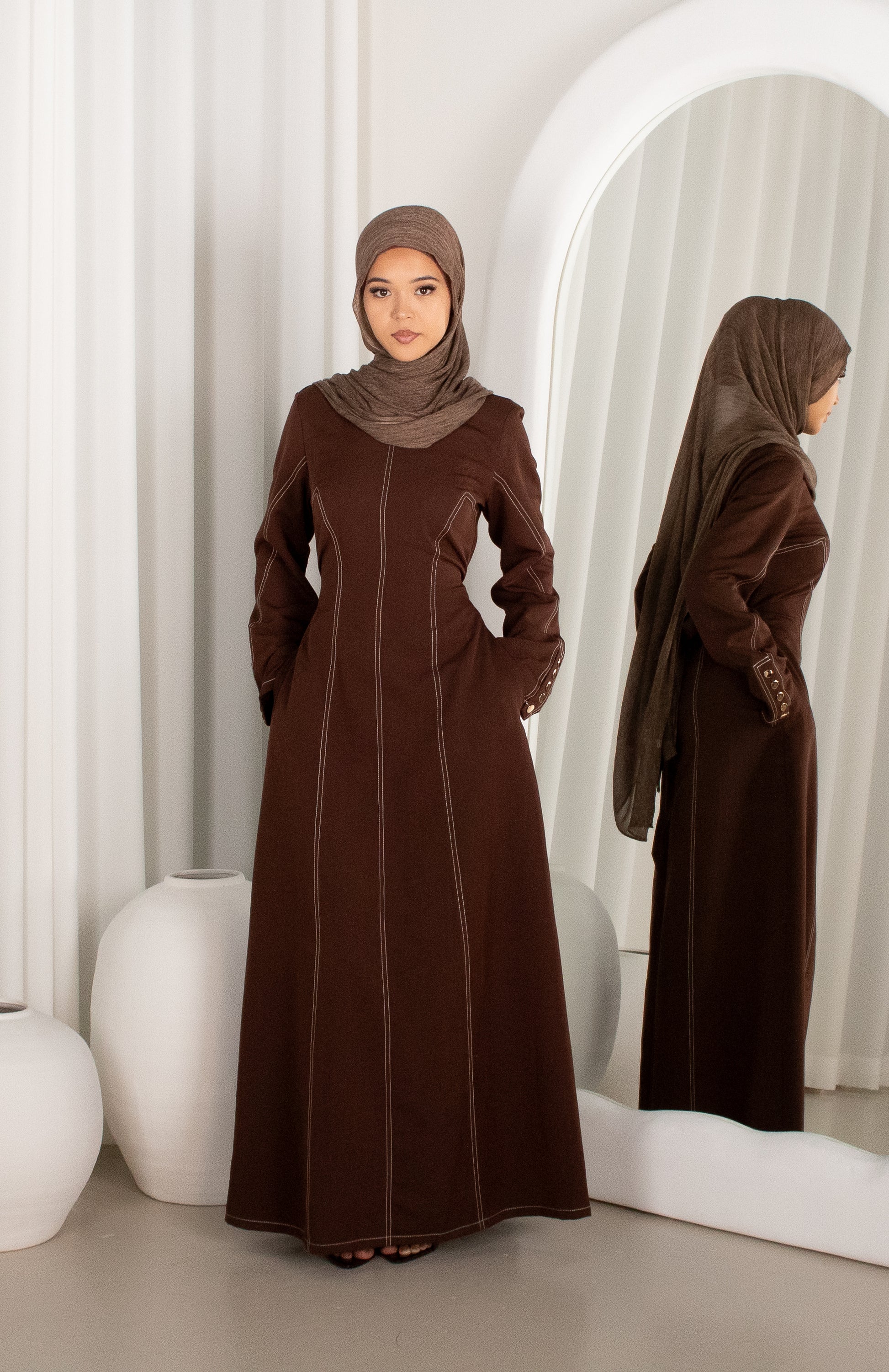 Woman wearing a brown abaya in a modern interior setting