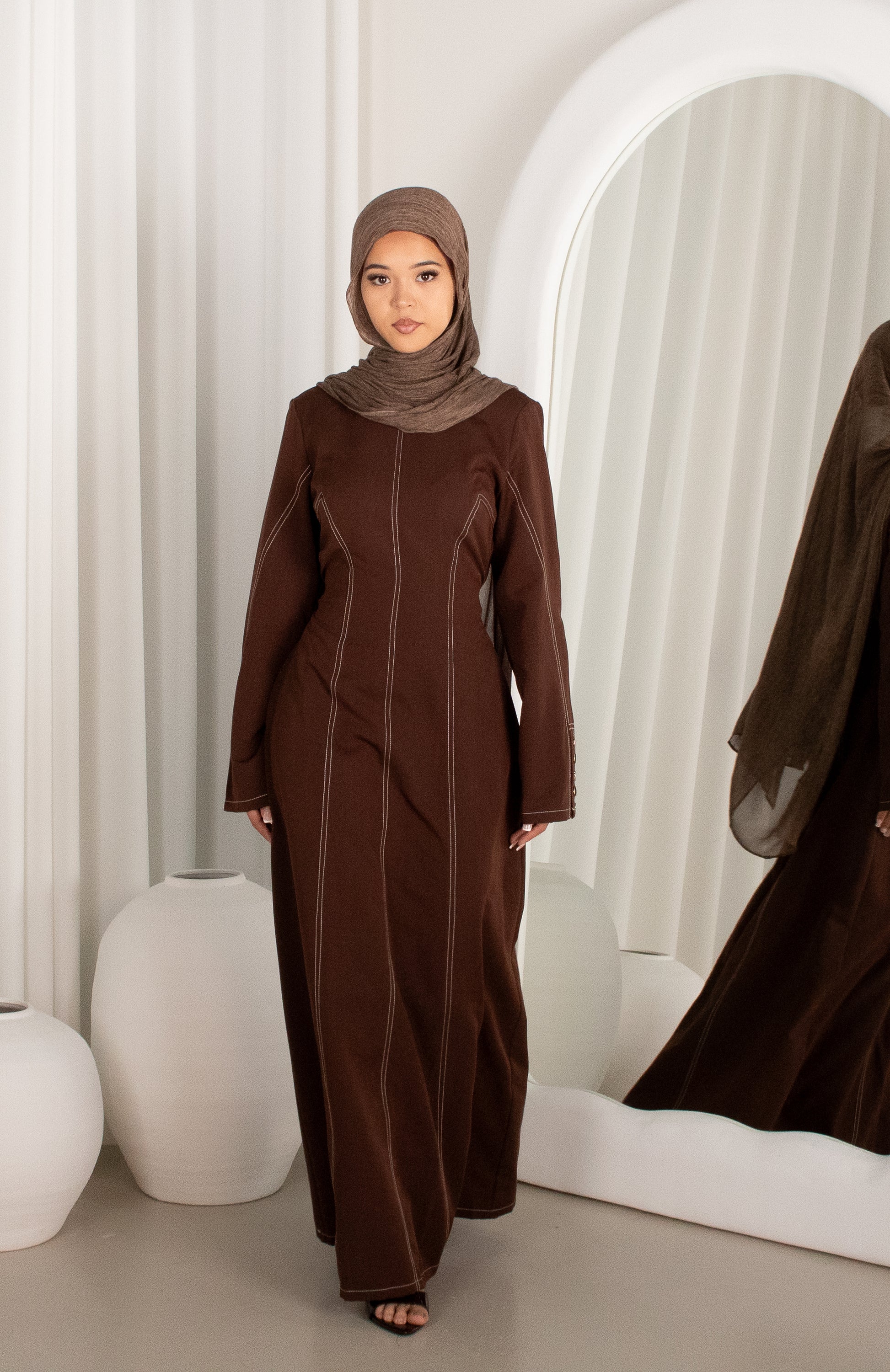 Woman wearing a brown abaya in a modern interior setting