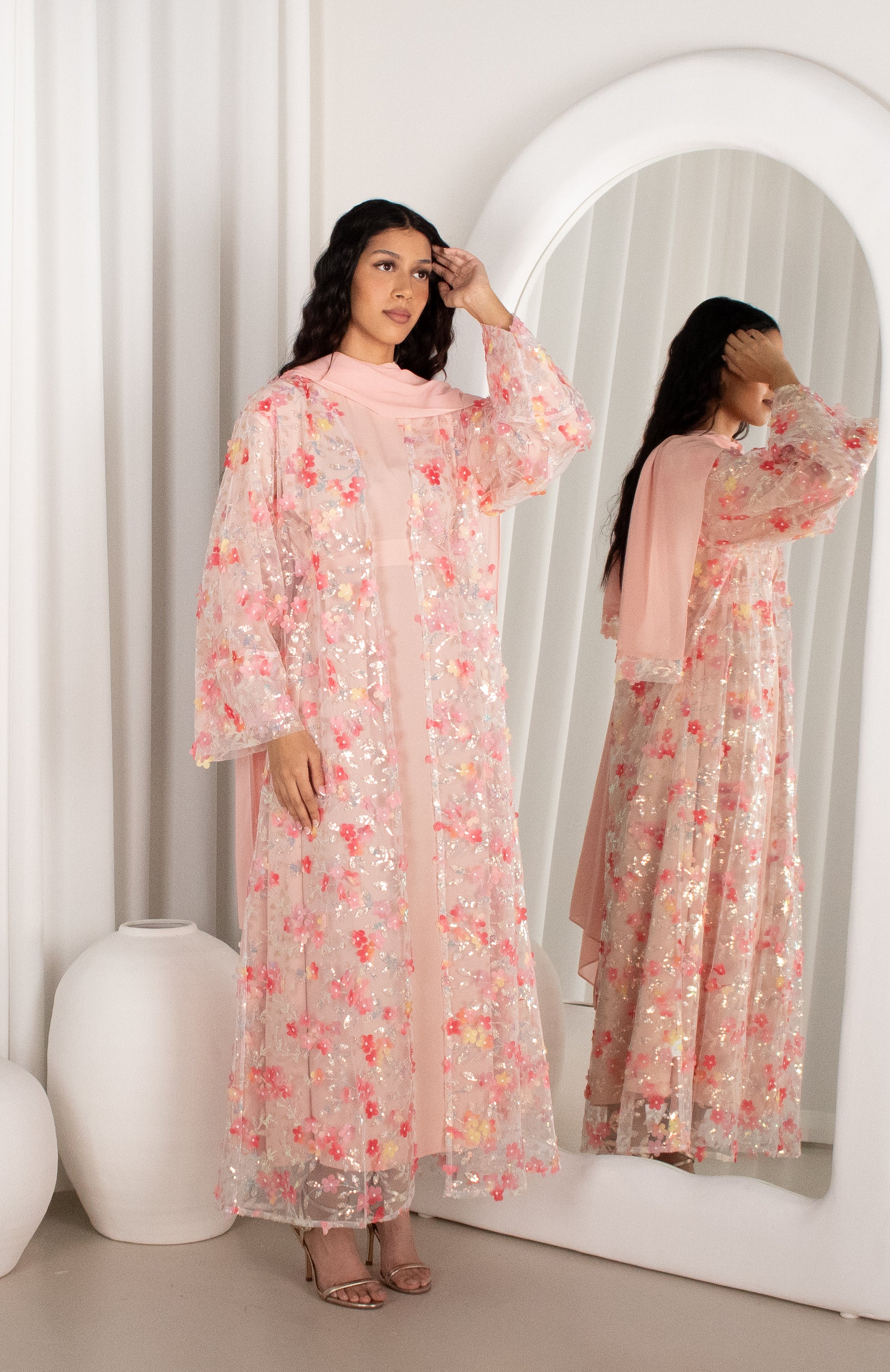 Woman wearing a floral dress standing in front of a mirror.