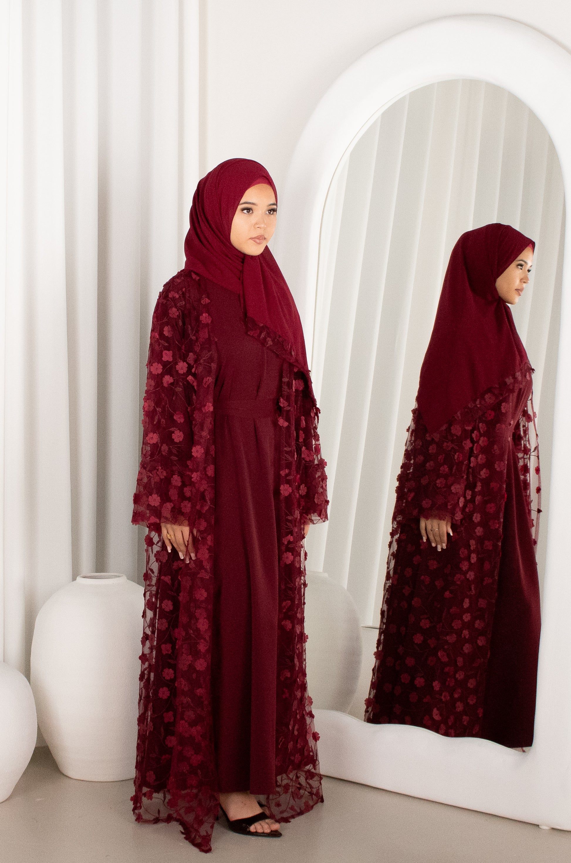 Woman in a burgundy floral dress standing in front of a mirror.