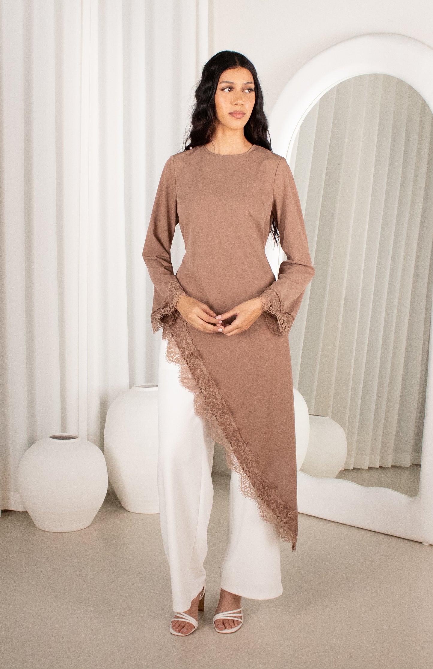 Woman wearing a brown dress with lace details in a minimalistic setting