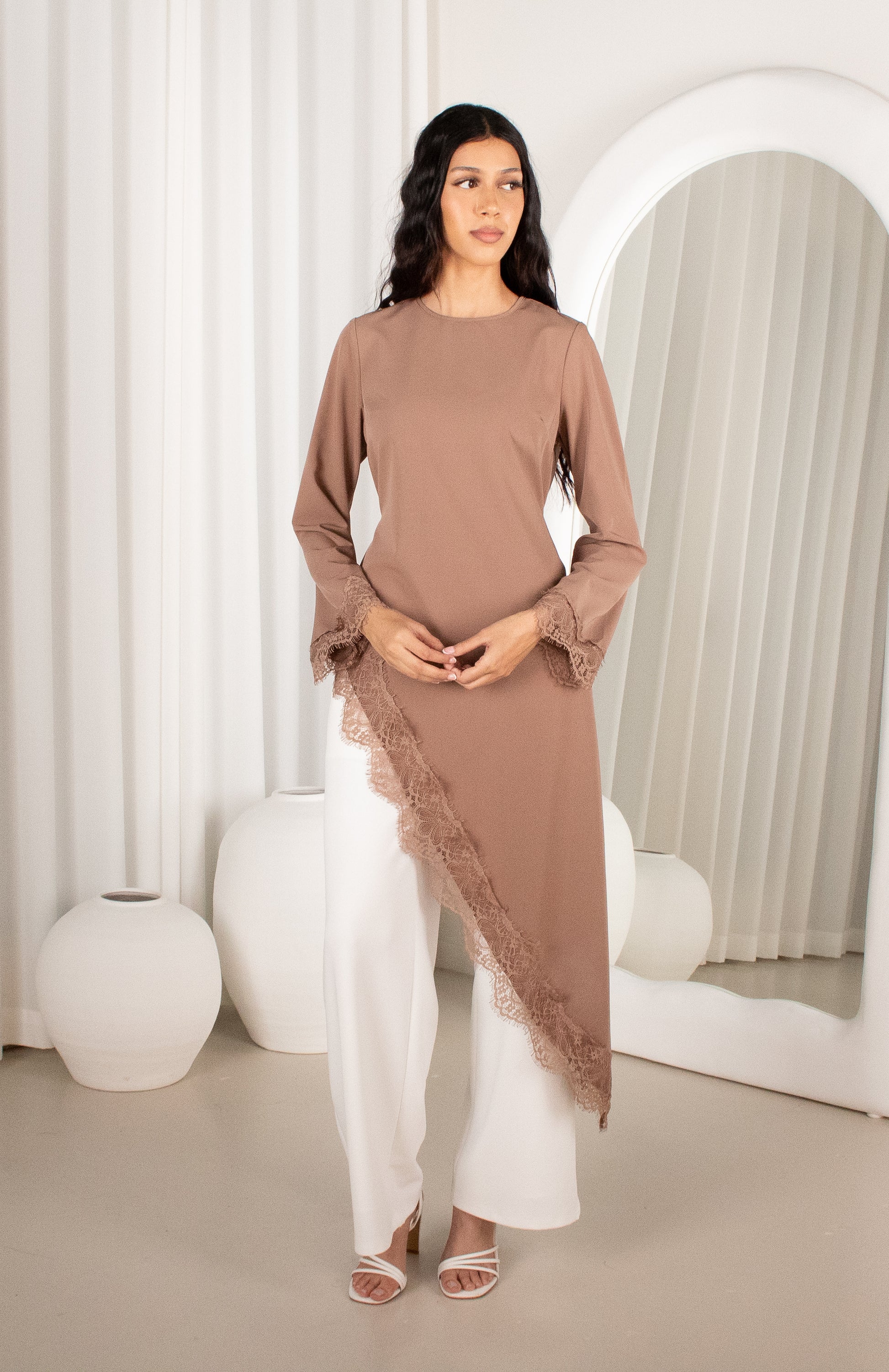 Woman wearing a brown dress with lace details in a minimalistic setting