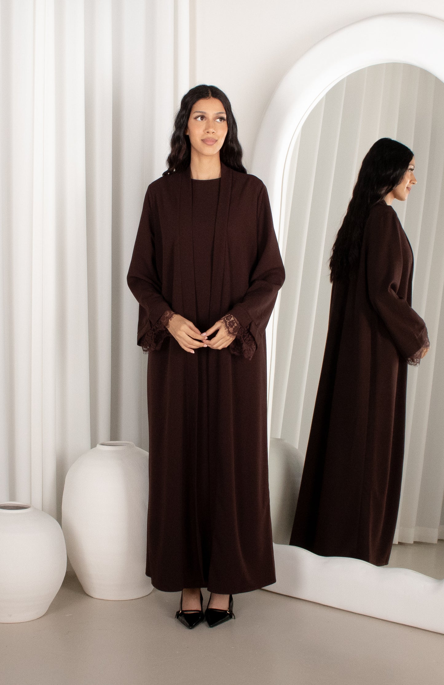 Woman wearing a brown long dress standing in front of a mirror.