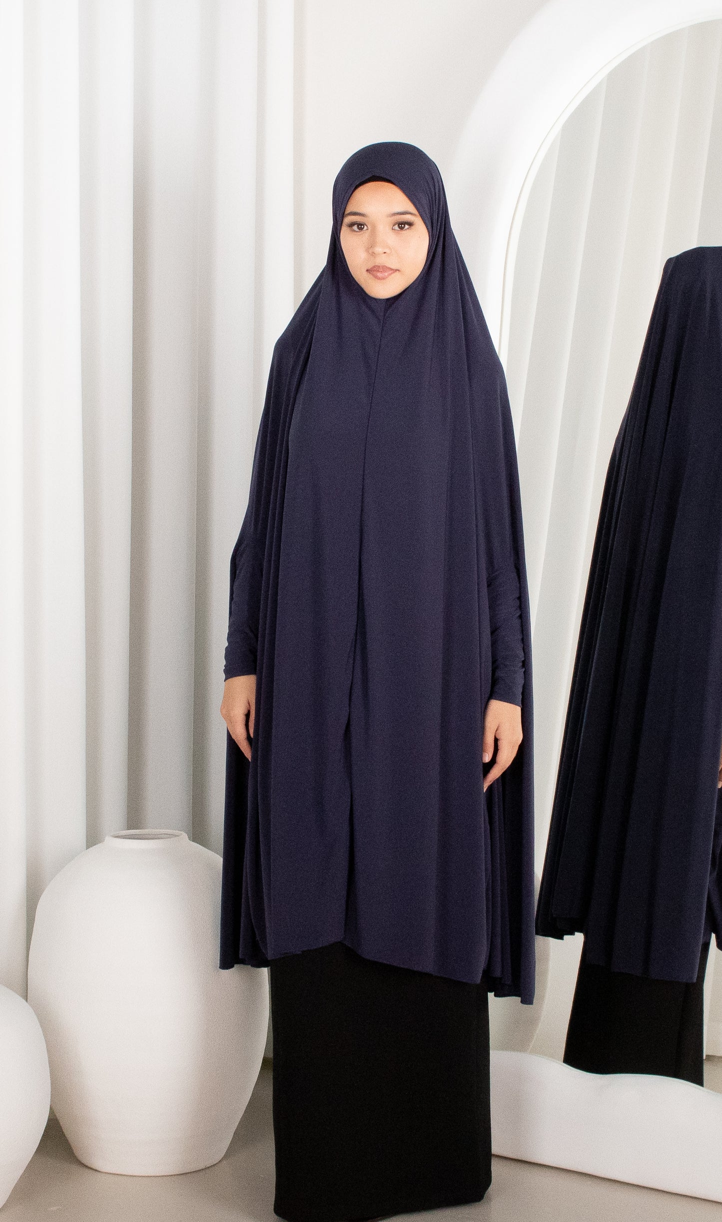 Woman wearing a navy abaya in a minimalistic setting