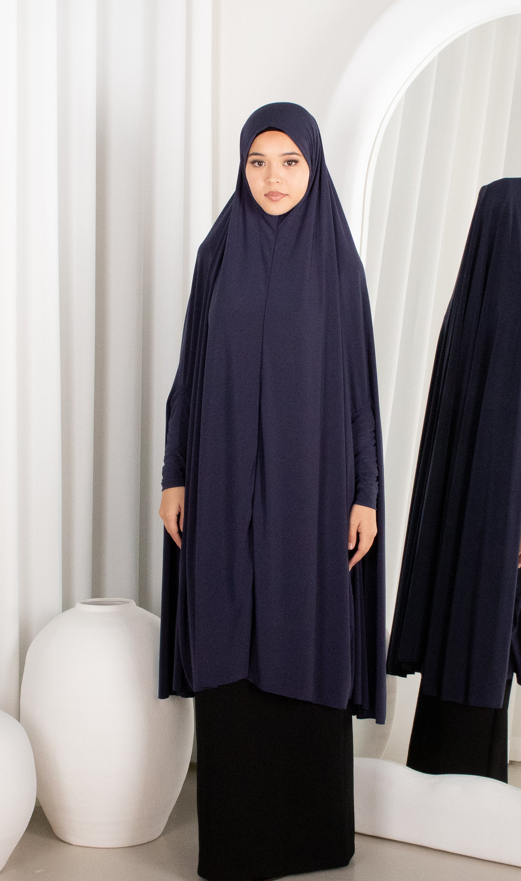 Woman wearing a navy abaya in a minimalistic setting