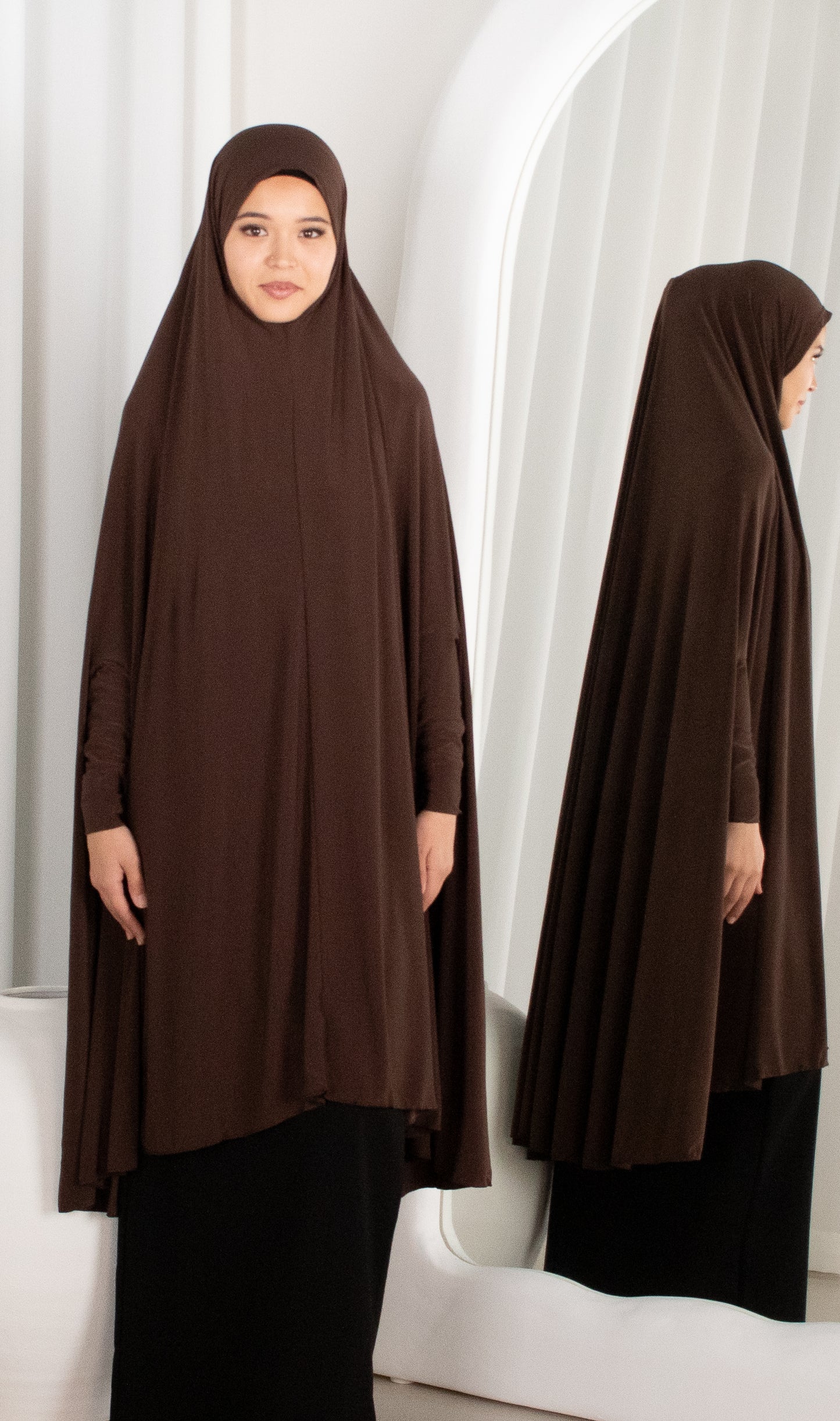 Woman wearing a brown abaya in a white room