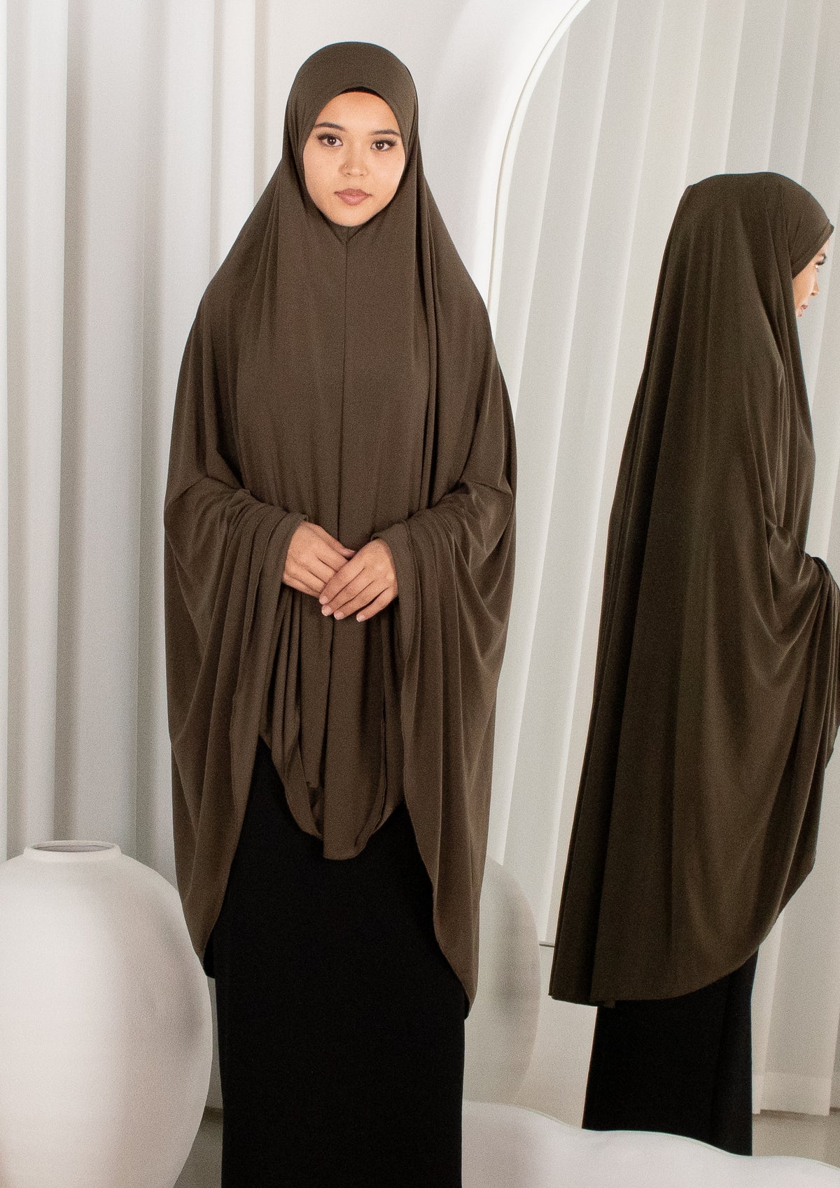 Woman wearing a brown hijab in front of a white curtain